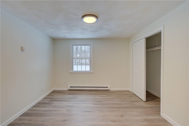 247 Quaker Ln, Scituate, RI 02857 - unfurnished bedroom featuring a baseboard heating unit, light wood-type flooring, a closet, and baseboards