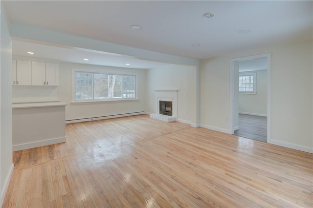 247 Quaker Ln, Scituate, RI 02857 - unfurnished living room with a baseboard radiator, a fireplace, light wood-type flooring, baseboards, and recessed lighting