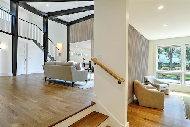 staircase with wood finished floors, a towering ceiling, baseboards, recessed lighting, and beam ceiling