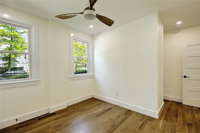 unfurnished room with healthy amount of natural light, wood finished floors, baseboards, and recessed lighting