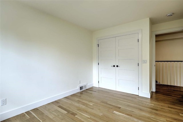 unfurnished bedroom with light wood-style flooring, a closet, and baseboards