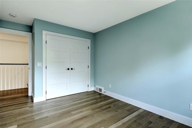 unfurnished bedroom with a closet, wood finished floors, and baseboards