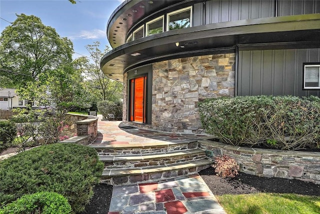property entrance with stone siding and board and batten siding