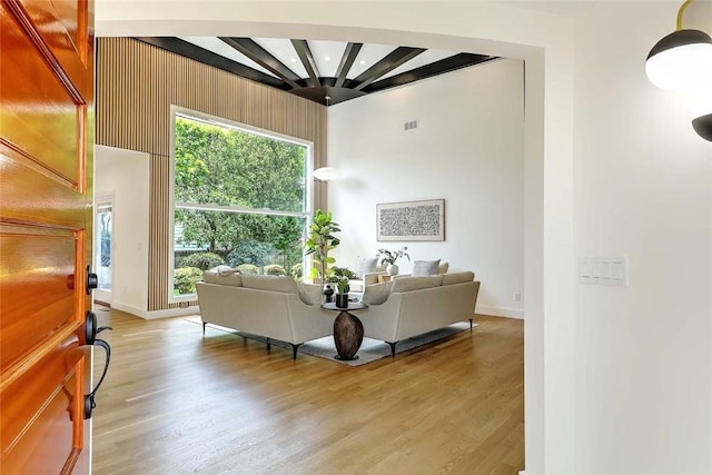 living area with light wood finished floors, baseboards, plenty of natural light, and beam ceiling