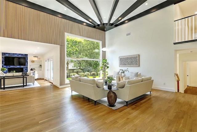 living room with a towering ceiling, baseboards, beamed ceiling, wood finished floors, and recessed lighting
