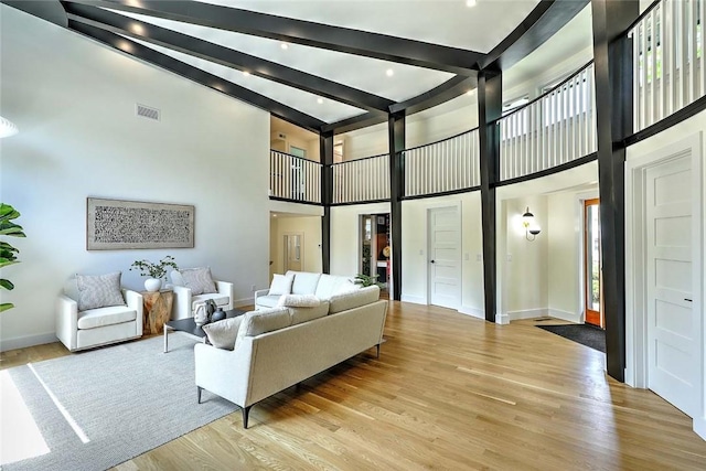 living room featuring high vaulted ceiling, baseboards, beam ceiling, and light wood-style flooring