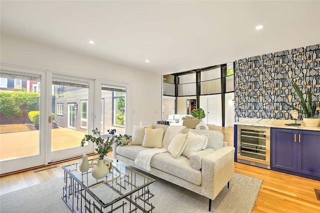living room with beverage cooler, bar area, light wood-style floors, and recessed lighting