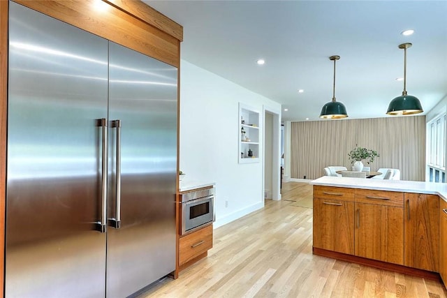 kitchen featuring built in refrigerator, brown cabinetry, light wood-style floors, recessed lighting, and light countertops