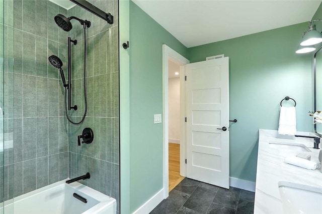 bathroom featuring a sink, a tile shower, and baseboards