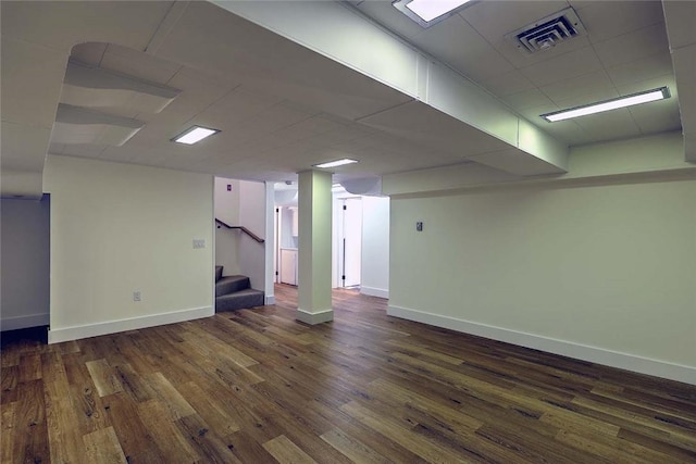 finished basement featuring wood finished floors, baseboards, stairway, and a drop ceiling