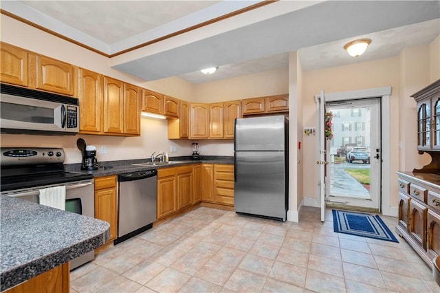 kitchen with stainless steel appliances, a sink, light tile patterned flooring, dark countertops, and baseboards