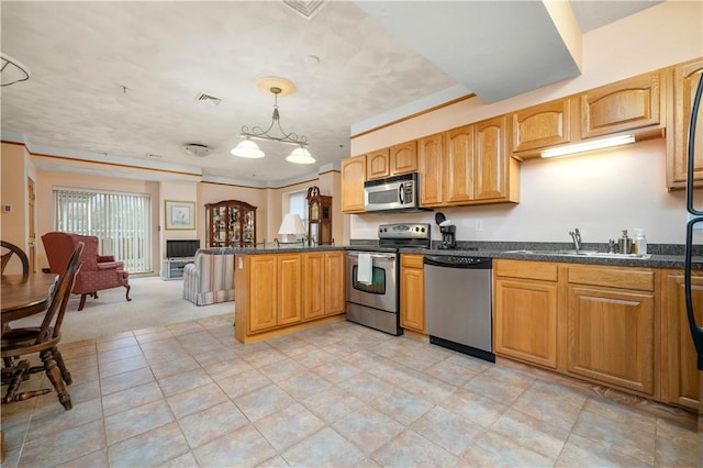 kitchen featuring appliances with stainless steel finishes, a sink, a peninsula, open floor plan, and pendant lighting
