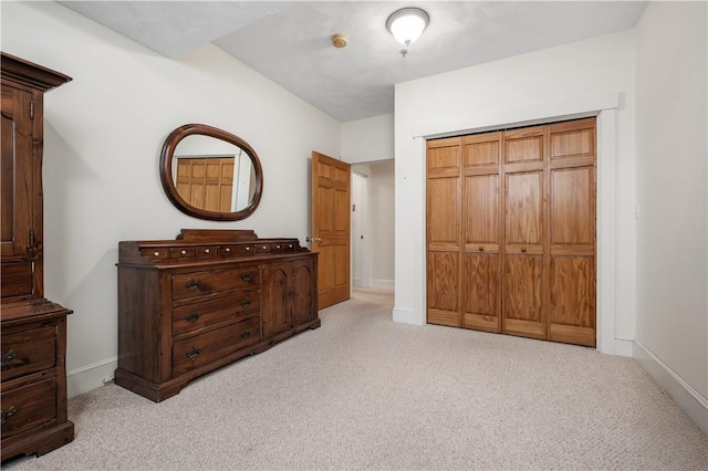 bedroom with light colored carpet, baseboards, and a closet