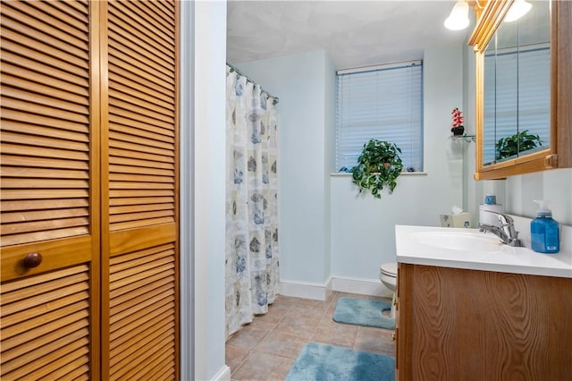 bathroom with a closet, vanity, tile patterned floors, and baseboards