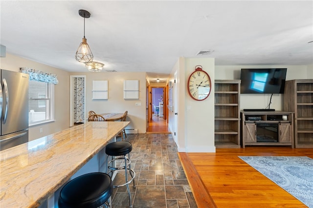 211 Iroquois Rd, Cumberland, RI 02864 - kitchen featuring freestanding refrigerator, light stone countertops, a kitchen breakfast bar, pendant lighting, and baseboards