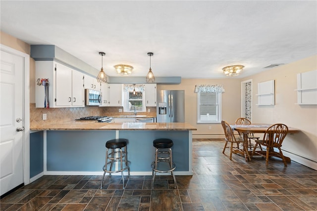 211 Iroquois Rd, Cumberland, RI 02864 - kitchen with stainless steel appliances, a peninsula, stone finish floors, white cabinets, and a kitchen bar