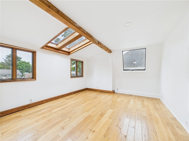 additional living space featuring a skylight, hardwood / wood-style flooring, and baseboards