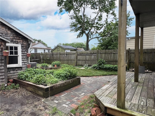 fenced backyard with a wooden deck and a vegetable garden