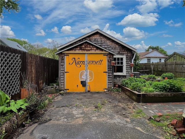 view of outdoor structure with fence and an outbuilding