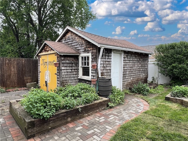 view of outbuilding with a vegetable garden, fence, and an outdoor structure