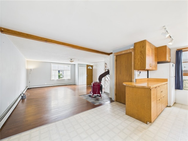 kitchen featuring a baseboard heating unit, a wood stove, light flooring, freestanding refrigerator, and light countertops