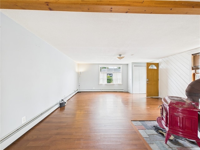 living area featuring wood finished floors, baseboard heating, a wood stove, and baseboards