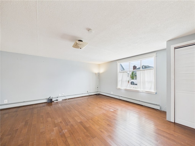 empty room featuring a textured ceiling, wood-type flooring, and a baseboard radiator