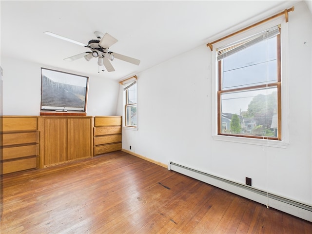 spare room with a baseboard radiator, light wood-style flooring, and ceiling fan