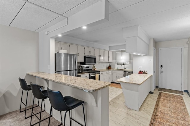 143 Hoffman Ave Unit 210, Cranston, RI 02920 - kitchen with stainless steel appliances, a peninsula, light stone countertops, and white cabinets