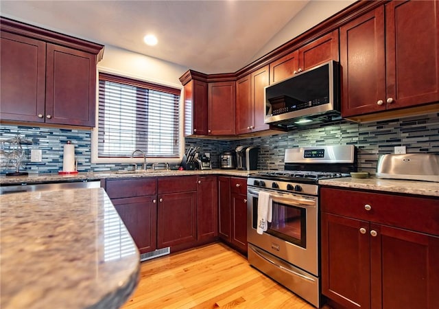 10 Flanders St, Johnston, RI 02919 - kitchen with appliances with stainless steel finishes, a sink, light wood-style floors, decorative backsplash, and vaulted ceiling
