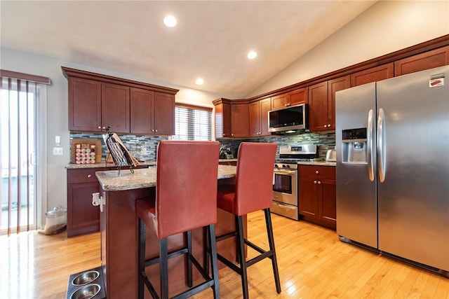 10 Flanders St, Johnston, RI 02919 - kitchen with appliances with stainless steel finishes, tasteful backsplash, a center island, a breakfast bar area, and lofted ceiling