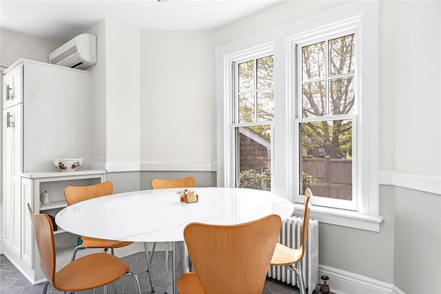 286 Kingstown Rd, Narragansett, RI 02882 - dining area with a wall unit AC, radiator heating unit, baseboards, and dark tile patterned flooring