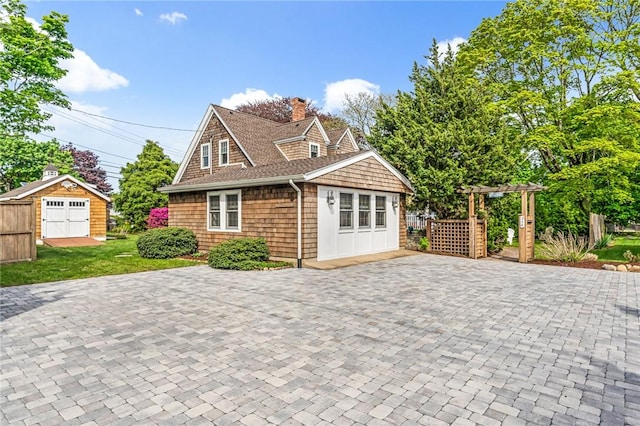 286 Kingstown Rd, Narragansett, RI 02882 - shingle-style home with a chimney, a storage unit, an outbuilding, a shingled roof, and driveway