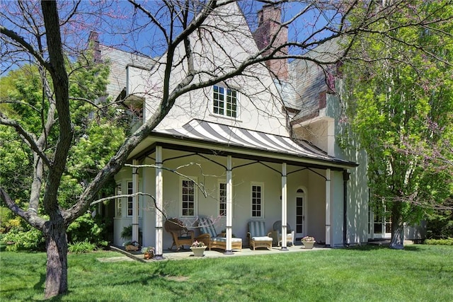 14 Leroy Ave, Newport, RI 02840 - view of front of home with a standing seam roof, a chimney, stucco siding, covered porch, and a front lawn