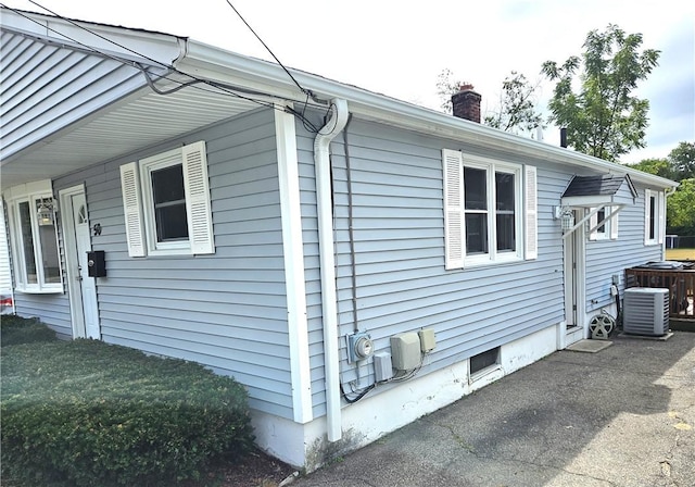view of home's exterior with a chimney and central AC