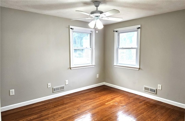 spare room featuring wood finished floors, ceiling fan, plenty of natural light, and baseboards