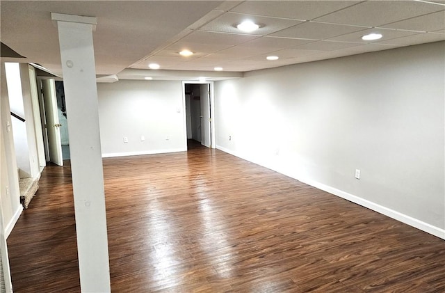 finished basement featuring recessed lighting, baseboards, wood finished floors, stairway, and a drop ceiling