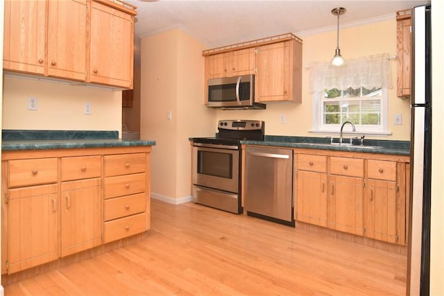 kitchen featuring stainless steel appliances, dark countertops, a sink, crown molding, and light wood-type flooring