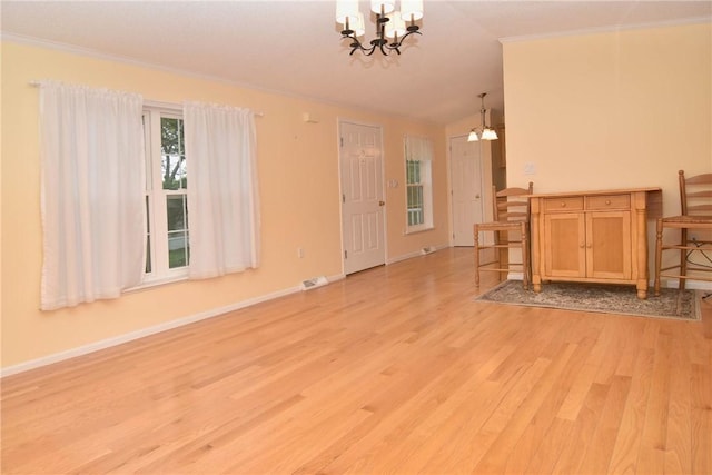 unfurnished living room featuring a chandelier, light wood-style flooring, baseboards, ornamental molding, and lofted ceiling