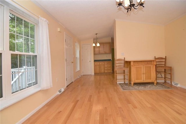 unfurnished dining area with a chandelier, light wood-style flooring, lofted ceiling, baseboards, and ornamental molding