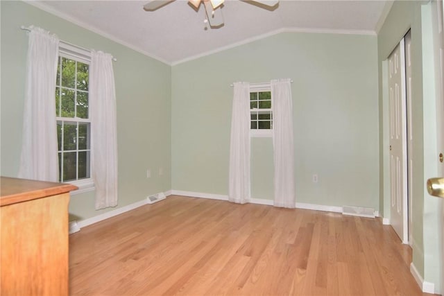 spare room with a ceiling fan, ornamental molding, light wood-style flooring, baseboards, and vaulted ceiling