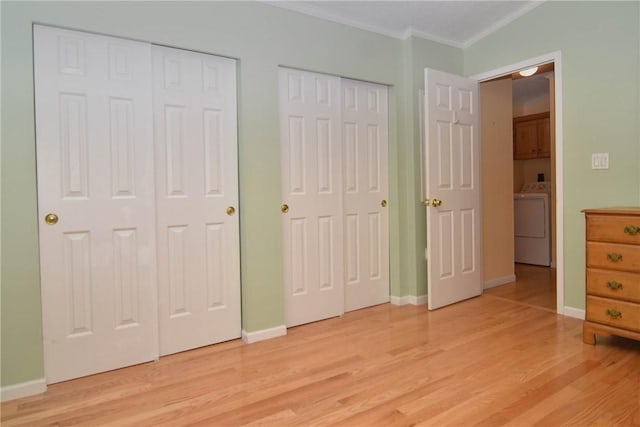unfurnished bedroom featuring washer / clothes dryer, multiple closets, crown molding, light wood-style floors, and baseboards