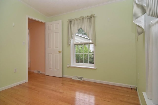 unfurnished room with wood finished floors, baseboards, and crown molding