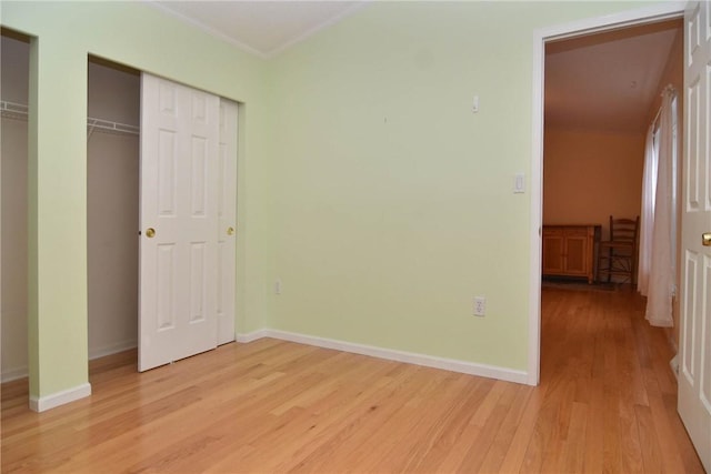 unfurnished bedroom featuring light wood-style floors, baseboards, and ornamental molding