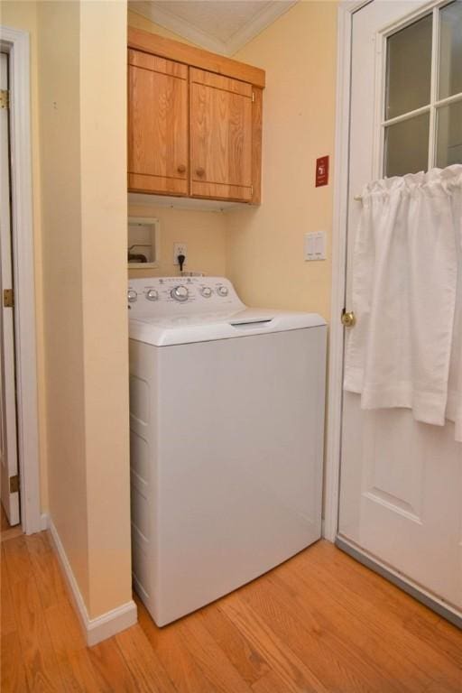 clothes washing area with washer / clothes dryer, cabinet space, light wood finished floors, crown molding, and baseboards