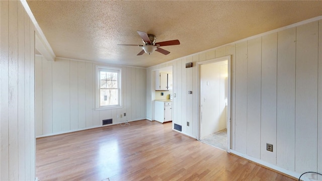 226 Marshall Ave, Cumberland, RI 02864 - unfurnished bedroom featuring light wood-style flooring, a textured ceiling, a ceiling fan, and wood walls
