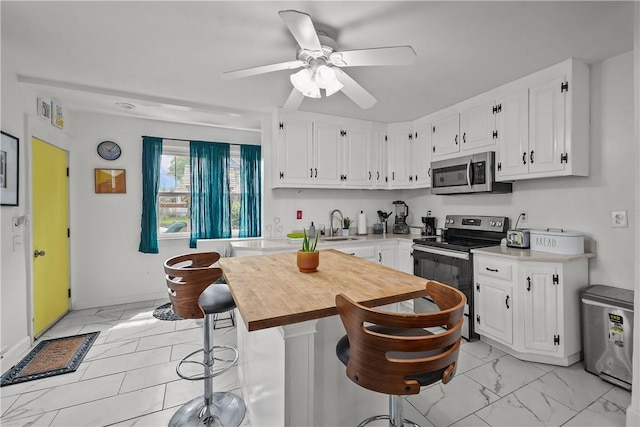54 Delway Rd, East Providence, RI 02914 - kitchen with appliances with stainless steel finishes, light marble finish flooring, white cabinetry, ceiling fan, and a breakfast bar area