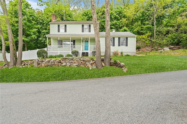 view of front of property with a chimney, a porch, and view of scattered trees