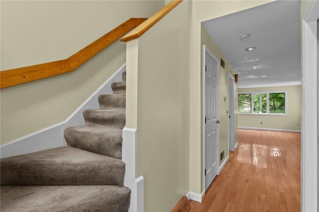 stairs featuring wood finished floors, baseboards, and recessed lighting