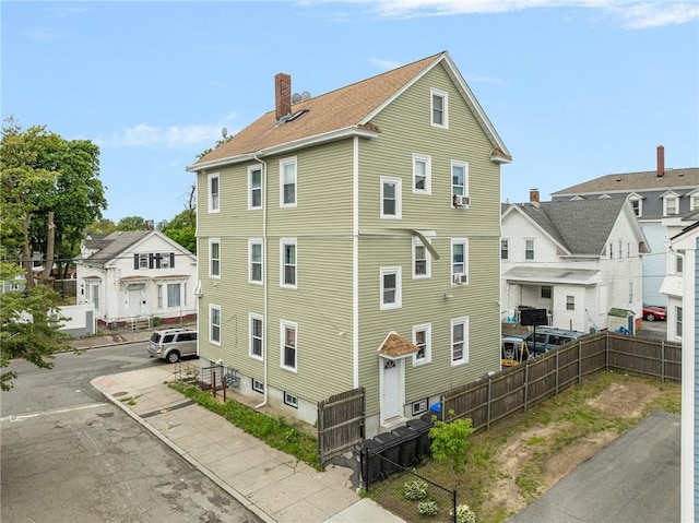69 Potters Ave, Providence, RI 02905 - view of property exterior featuring a chimney and uncovered parking
